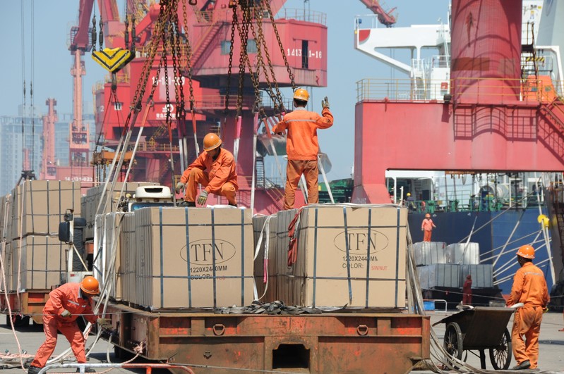Workers load goods for export onto a crane at a port in Lianyungang