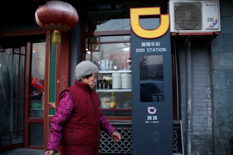 Woman walks past a sign of station for Didi Chuxing in Beijing