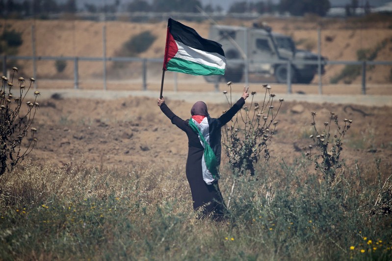 FILE PHOTO: Woman holding a Palestinian flag gestures in front of Israeli forces during protest marking the 71st anniversary of 'Nakba' at the Israel-Gaza border fence in the southern Gaza Strip