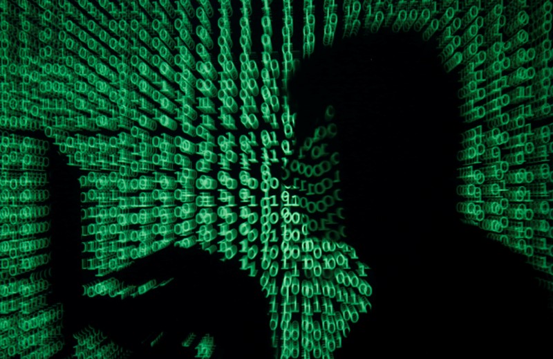 FILE PHOTO: Man holds laptop computer as cyber code is projected on him in this illustration picture
