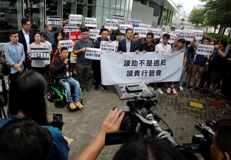 A group of assistants to members of the Legislative Council speak to the media as they hold placards outside the Legislative Council building in Hong Kong