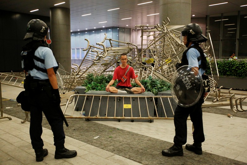 Police officers stand near a protester sitting during a protest to demand authorities scrap a proposed extradition bill with China, outside the Legislative Council in Hong Kong