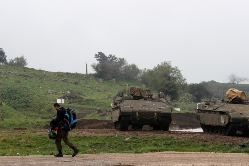 FILE PHOTO: An Israeli soldier walks past armoured Israeli military vehicles in the Israeli-occupied Golan Heights