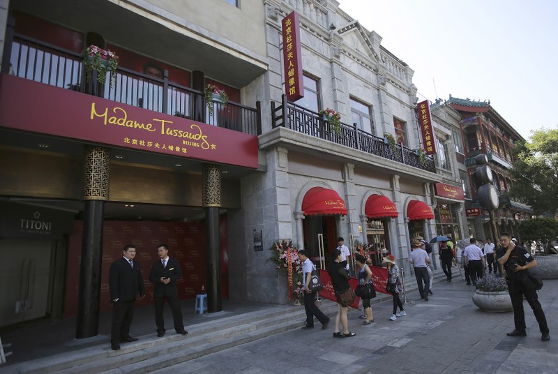Visitors walk past as security personnel keep watch outside a new Madame Tussauds Museum at the Qianmen Commercial street in central Beijing