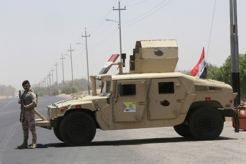 An Iraqi soldier stands next to a military vehicle at the entry of Zubair oilfield after a rocket struck the site of residential and operations headquarters of several oil companies in Basra