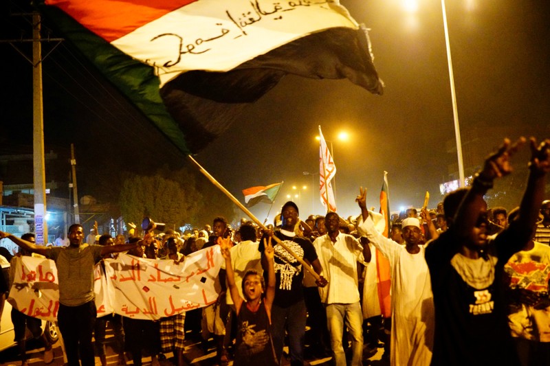 FILE PHOTO: Sudanese people chant slogans and wave Sudanese flags during a demonstration in Khartoum