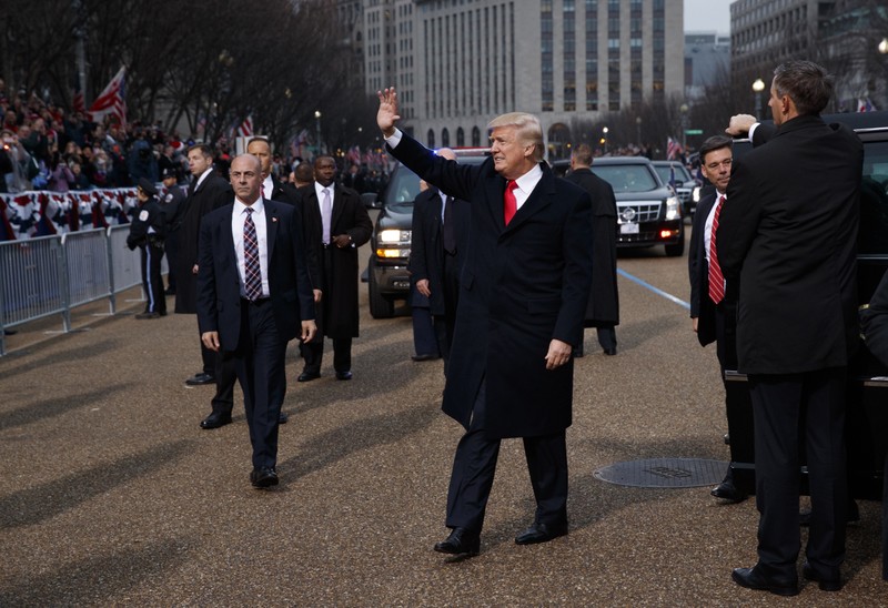 President Donald Trump waves as he walks near the White House in the inaugural parade in Washington