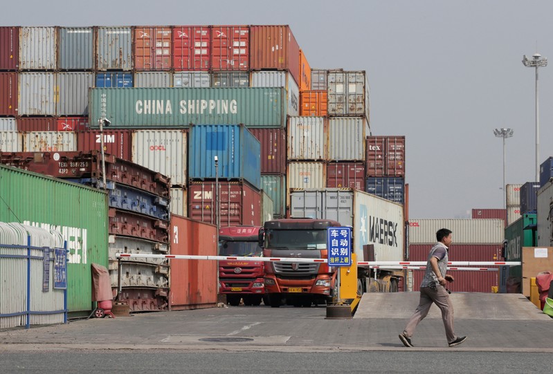 A man walks next to containers in a logistics center near Tianjin Port