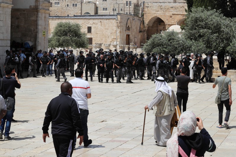 Palestinians stand near Israeli policemen as clashes erupted with Palestinians on 