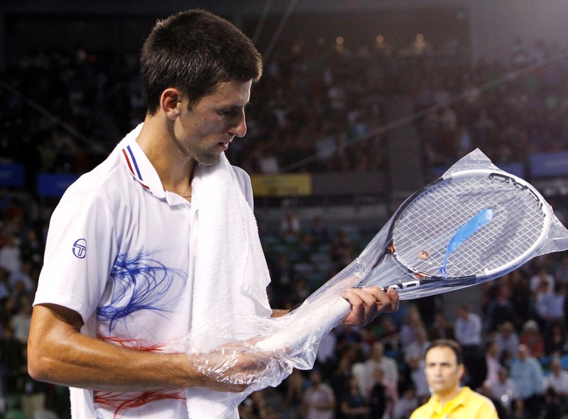 Djokovic of Serbia takes out a new racquet at the start of the third set against Ferrer of Spain during their quarter-final match at the Australian Open in Melbourne