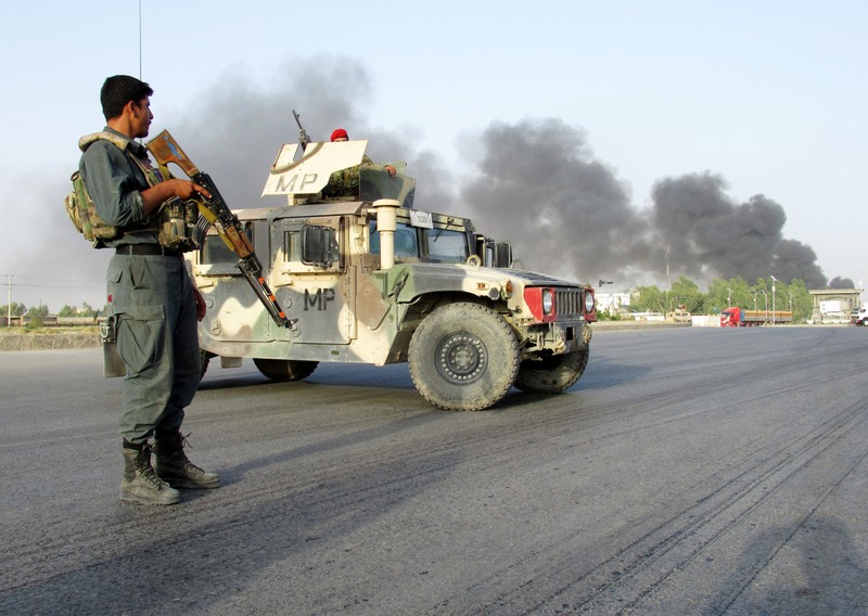 An Afghan police officer keeps watch near the site of a suicide car bomb blast in Kandahar