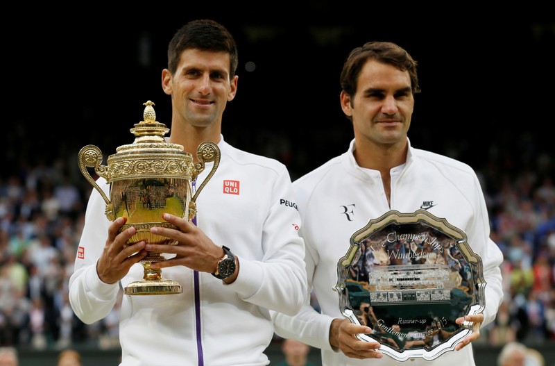 FILE PHOTO: Winner, Novak Djokovic of Serbia and runner up Roger Federer of Switzerland pose with their trophies after their Men's Singles Final match at the Wimbledon Tennis Championships in London
