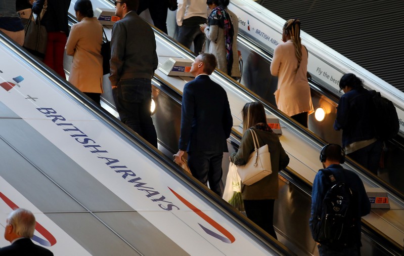 FILE PHOTO: Commuters pass a British Airways advert on the tube at Canary Wharf