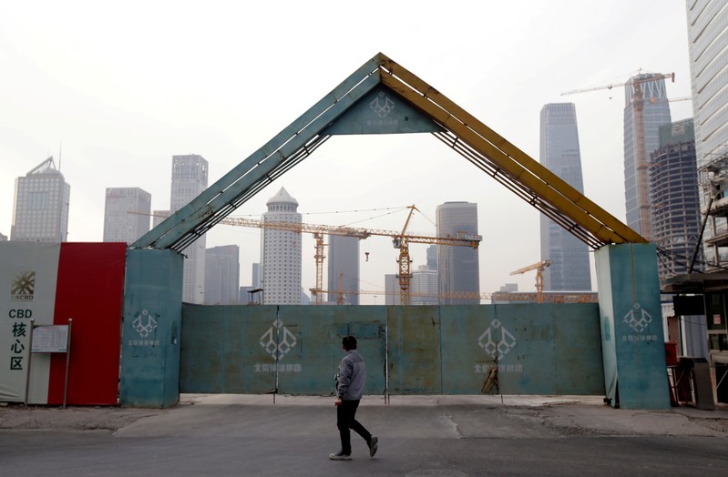 FILE PHOTO: A man walks outside the construction sites in Beijing's central business area