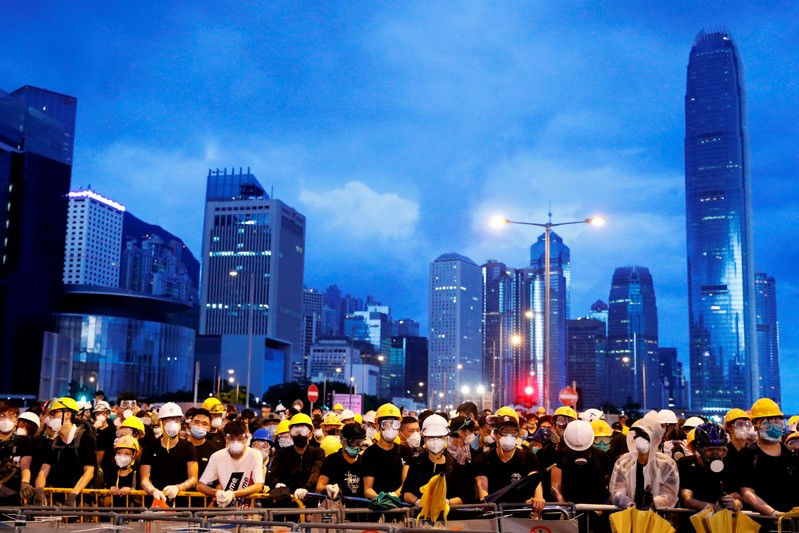FILE PHOTO: Anti-extradition bill protesters stand behind a barricade during a demonstration near a flag raising ceremony for the anniversary of Hong Kong handover to China in Hong Kong