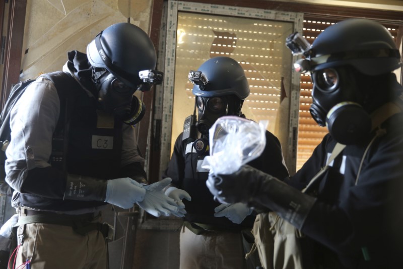 A U.N. chemical weapons expert holds a plastic bag containing samples from one of the sites of an alleged chemical weapons attack in Ain Tarma