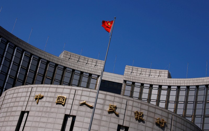 FILE PHOTO: A Chinese national flag flutters outside the headquarters of the People's Bank of China, the Chinese central bank, in Beijing, China