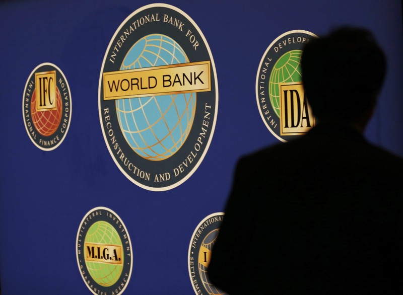 FILE PHOTO: A man is silhouetted against the logo of the World Bank at the main venue for the IMF and World Bank annual meeting in Tokyo