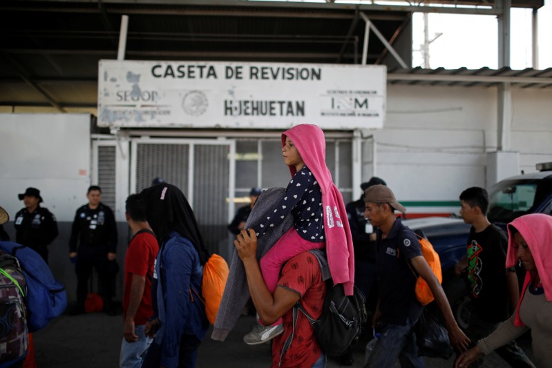 People belonging to a caravan of migrants from Honduras en route to the U.S. walk by an immigration checkpoint in Huehuetan