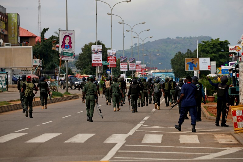 Members of the police head down Banex road during their operation to disperse members of the IMN from a street in Abuja