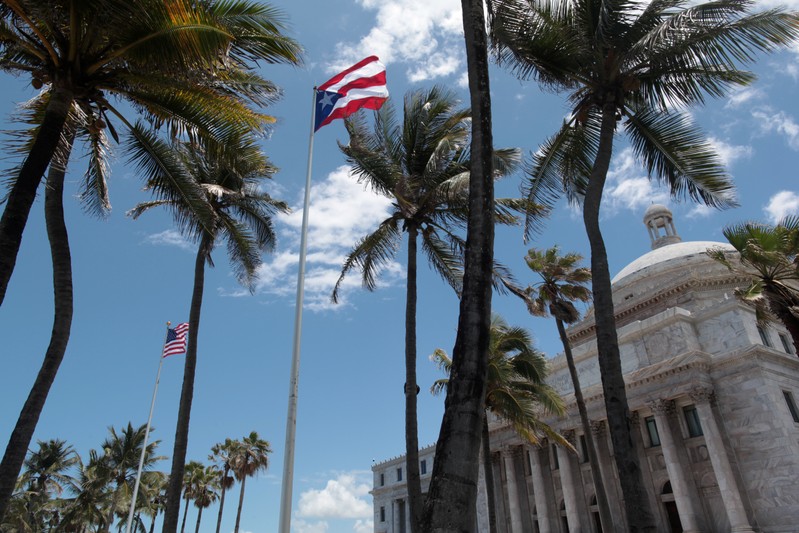 FILE PHOTO: The flags of the U.S. and Puerto Rico fly outside the Capitol building in San Juan