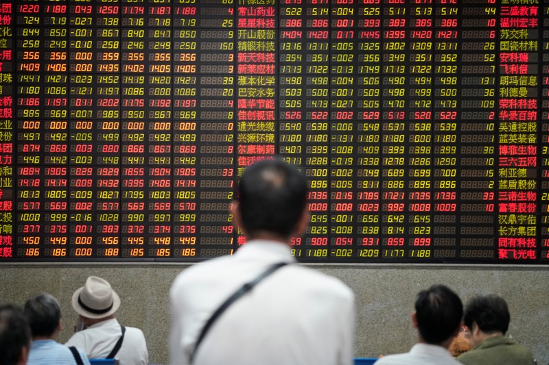 People look at an electronic board showing stock information at a brokerage house in Shanghai