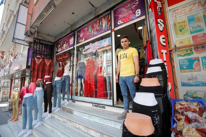 Syrian shopkeeper Mustafa poses in front of his clothes shop in Istanbul's Kucukcekmece district