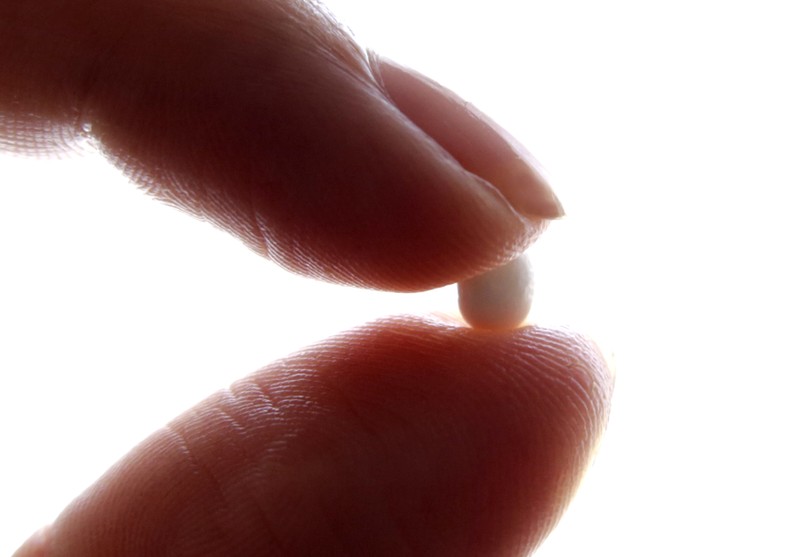 FILE PHOTO: An illustration picture shows a woman holding a pill at her home in Nice