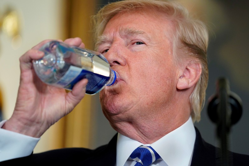 FILE PHOTO: U.S. President Donald Trump drinks while speaking about his recent trip to Asia at the White House in Washington