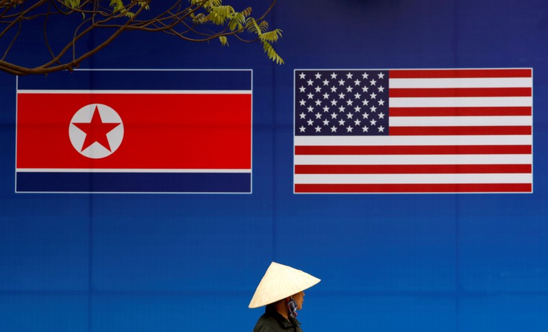 FILE PHOTO: A person walks past a banner showing North Korean and U.S. flags ahead of the North Korea-U.S. summit in Hanoi
