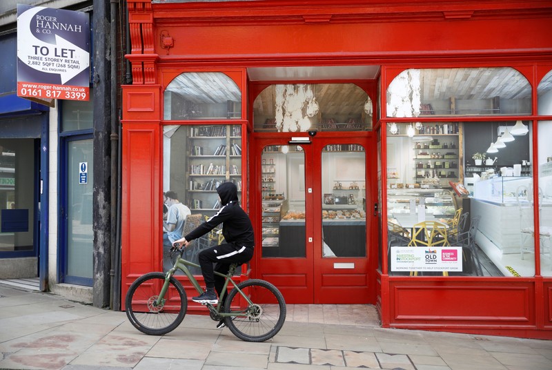 A boy cycles past a closed down retail unit for rent in Stockport, near Manchester