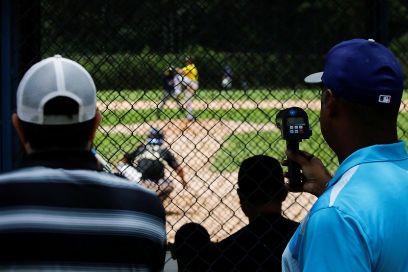 Trainers and scouts look at players during a baseball showcase in Caracas