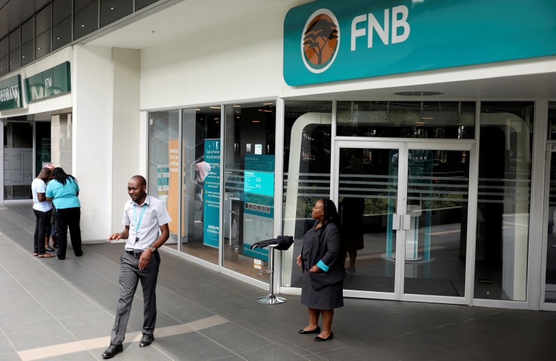 FILE PHOTO: First National Bank (FNB) staff members stand outside their bank to notify customers that the bank is closed due to load shedding, at the mall of the south in Johannesburg