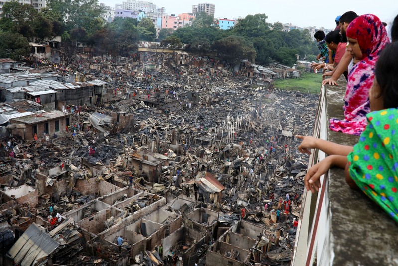 People look on to the slum that burnt out in Dhaka