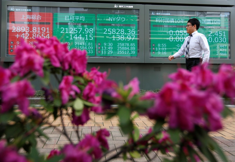 A passerby walks past in front of a stock quotation board outside a brokerage in Tokyo