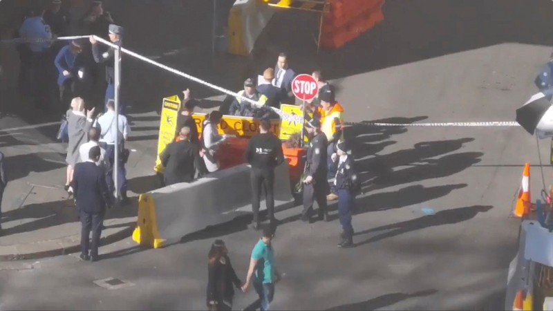 People walk past security officers standing around a barricaded area in Sydney
