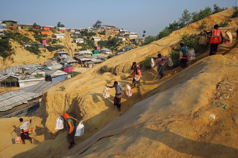 Rohingya refugees carry bricks to a construction site at the Balukhali camp in Cox's Bazar