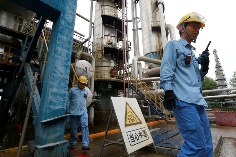 FILE PHOTO - Technicians walk down the refinery which produces ethanol gasoline for vehicles, at China's Petroleum and Chemical Corporation, or Sinopec, Tianjin company in Tianjin