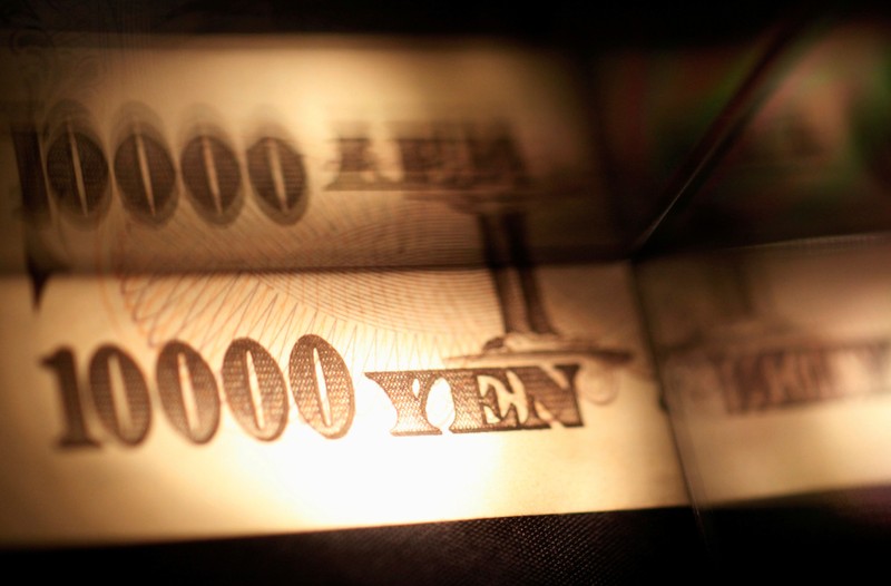 Light is cast on a Japanese 10,000 yen note as it's reflected in a plastic board in Tokyo, in this picture illustration