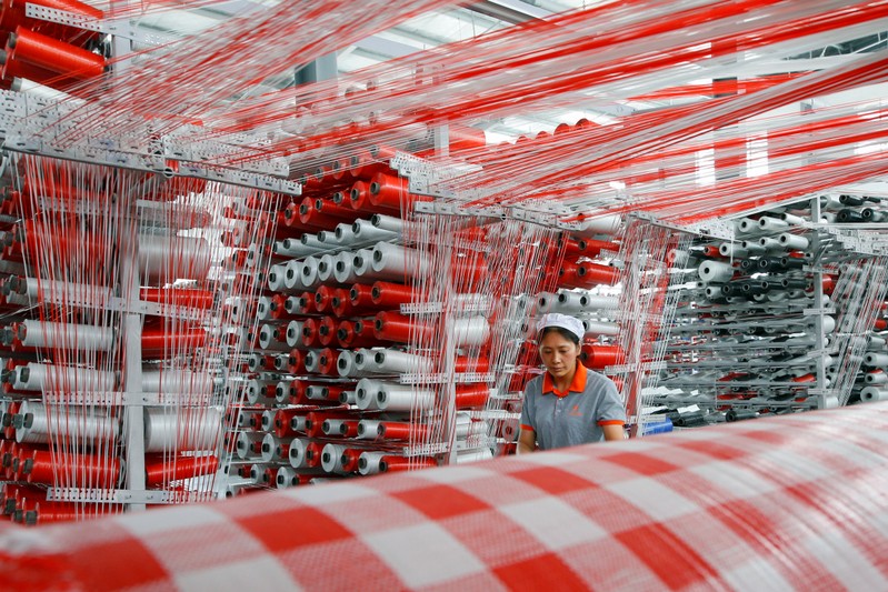 Woman works at a workshop manufacturing plastic woven materials for packaging products in Suqian, Jiangsu