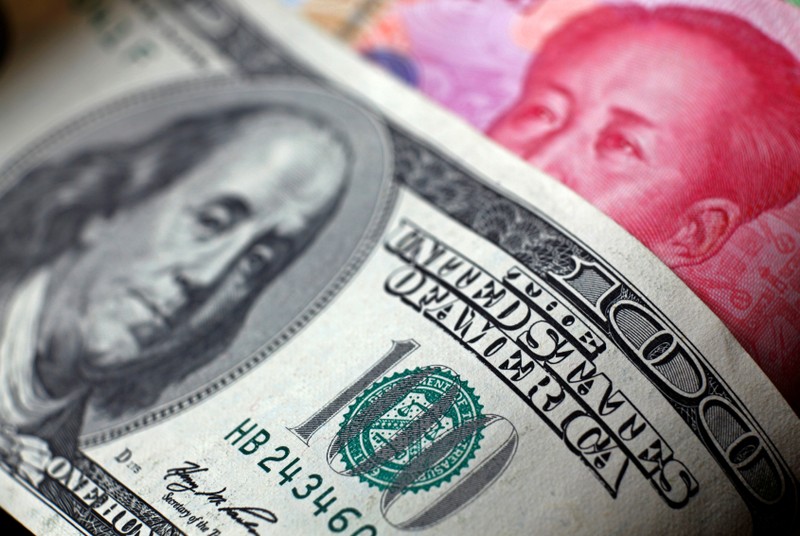 FILE PHOTO: File photo of a Chinese 100 yuan banknote being placed under a $100 banknote in this photo illustration taken in Beijing