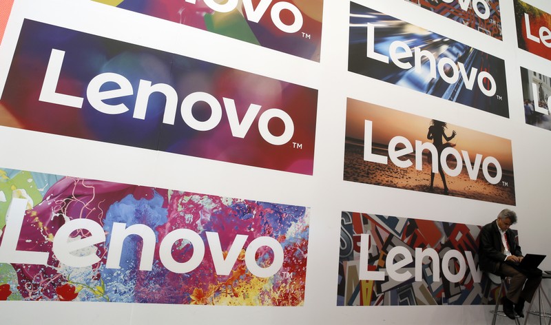 A man uses his laptop next to Lenovo's logos during the Mobile World Congress in Barcelona