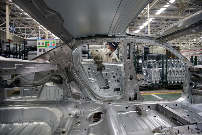 FILE PHOTO: An employee installs car doors at a production line of Dongfeng Peugeot Citroen Automobile factory in Wuhan