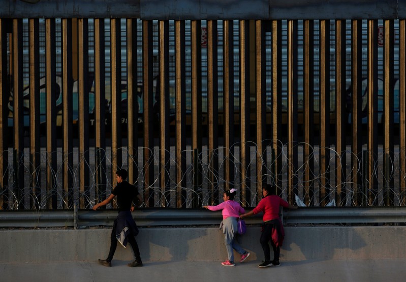 FILE PHOTO: An immigrant family walks along the border fence after crossing illegally to the United States to turn themselves in to the U.S. Customs and Border Protection officials to request for asylum in El Paso, Texas, as seen from Ciudad Juarez