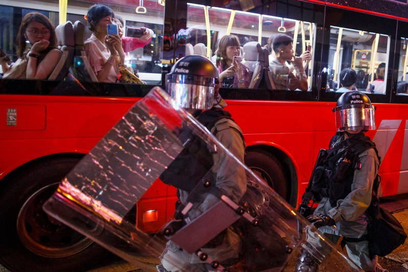 Passengers on a city bus watch riot police chase anti-government protesters down Nathan Road in Mong Kok in Hong Kong