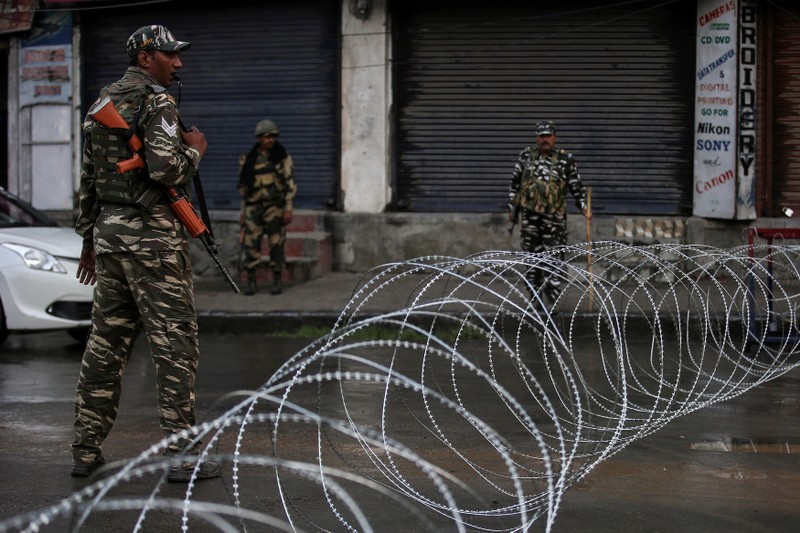 FILE PHOTO: Indian security forces personnel stand guard next to concertina wire laid across a road during restrictions after the government scrapped special status for Kashmir, in Srinagar