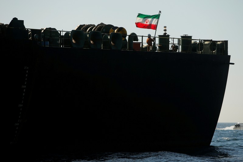 FILE PHOTO: A crew member raises the Iranian flag on Iranian oil tanker Adrian Darya 1, previously named Grace 1, as it sits anchored after the Supreme Court of the British territory lifted its detention order, in the Strait of Gibraltar