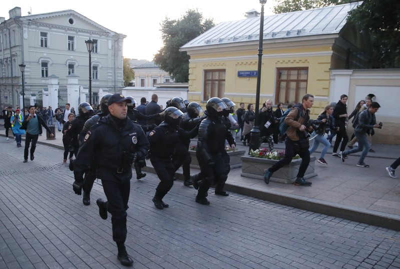 Law enforcement officers run along a street after a rally to demand authorities allow opposition candidates to run in a local election in Moscow