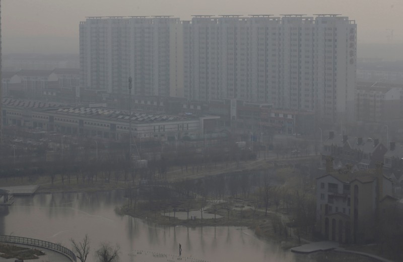 FILE PHOTO: A resident walks on a frozen lake near apartment blocks on the outskirts of Tianjin