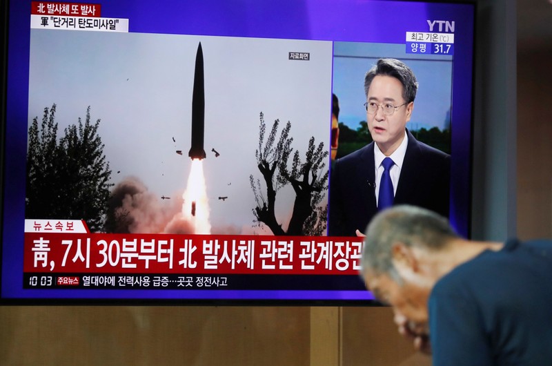 A man watches a TV showing a file picture for a news report on North Korea firing two unidentified projectiles, in Seoul